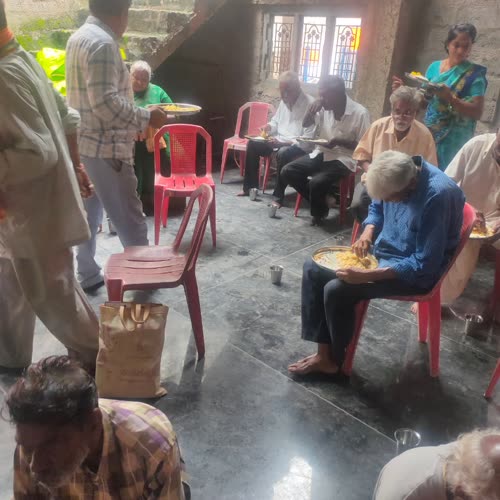 Devotees seated on chairs, eating their meal